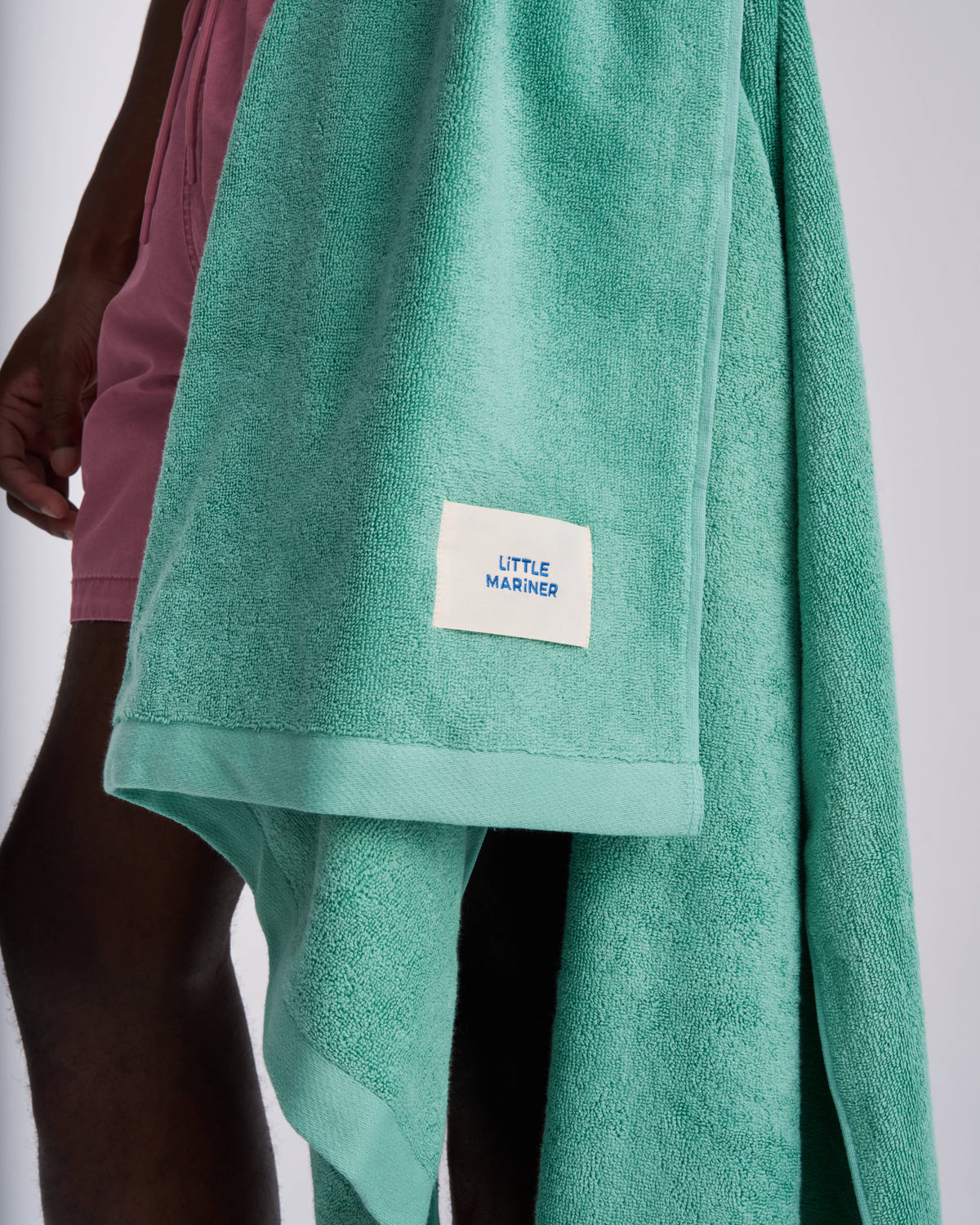 Sage Green organic cotton terry towel carried over the arm, woven label showing
