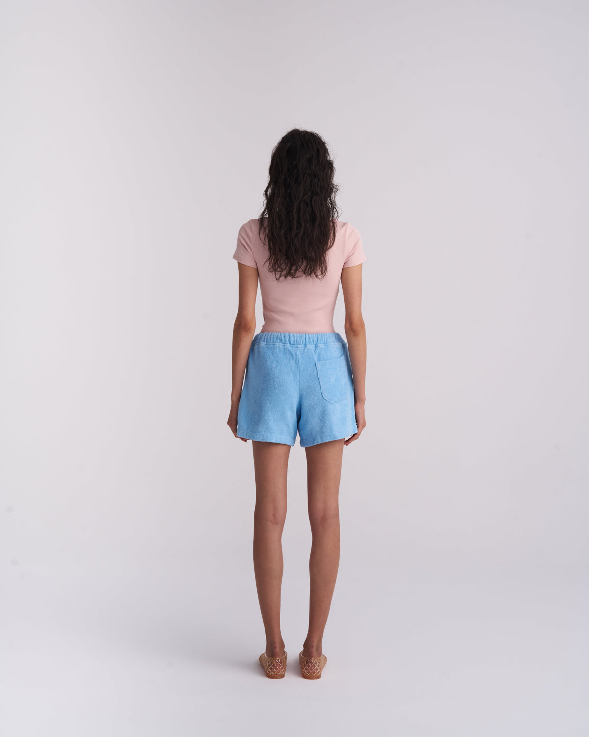 Back view of a woman wearing Coastal Blue organic cotton terry shorts with a back pocket
