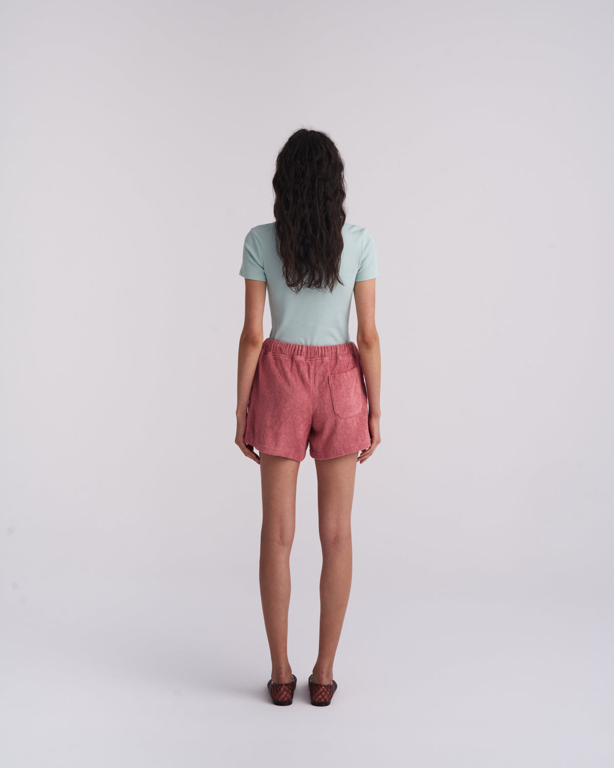 Back view of a woman wearing Dusty Rose organic cotton terry shorts with a back pocket