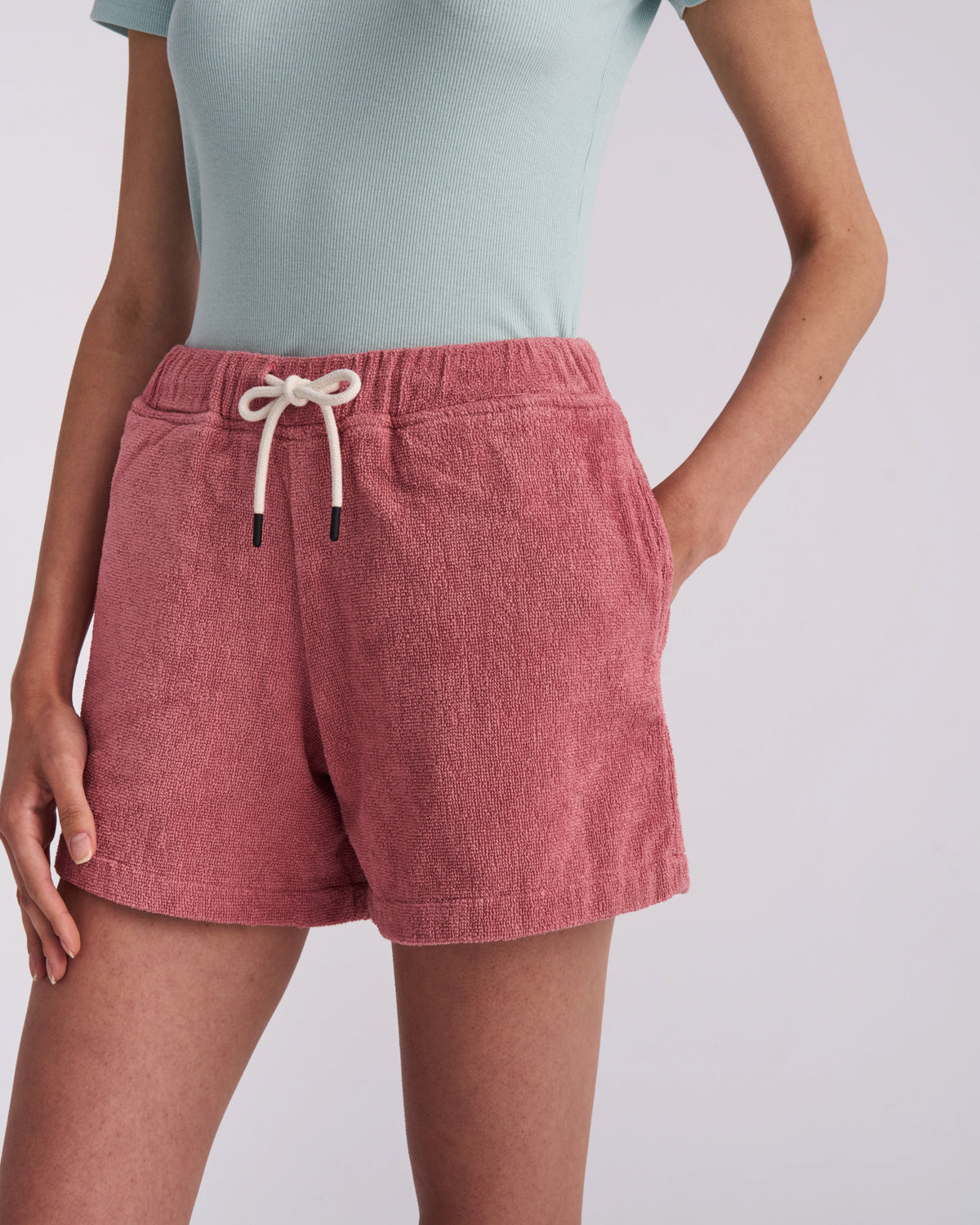 Dusty Rose women's organic cotton terry shorts worn with a hand in the side pocket