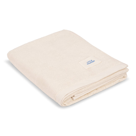 Folded off-white premium organic cotton terry towel by Little Mariner with branded label.