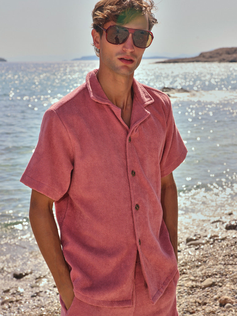 Man on beach wearing dusty rose organic cotton terry shirt and shorts by Little Mariner, styled as casual summer set.