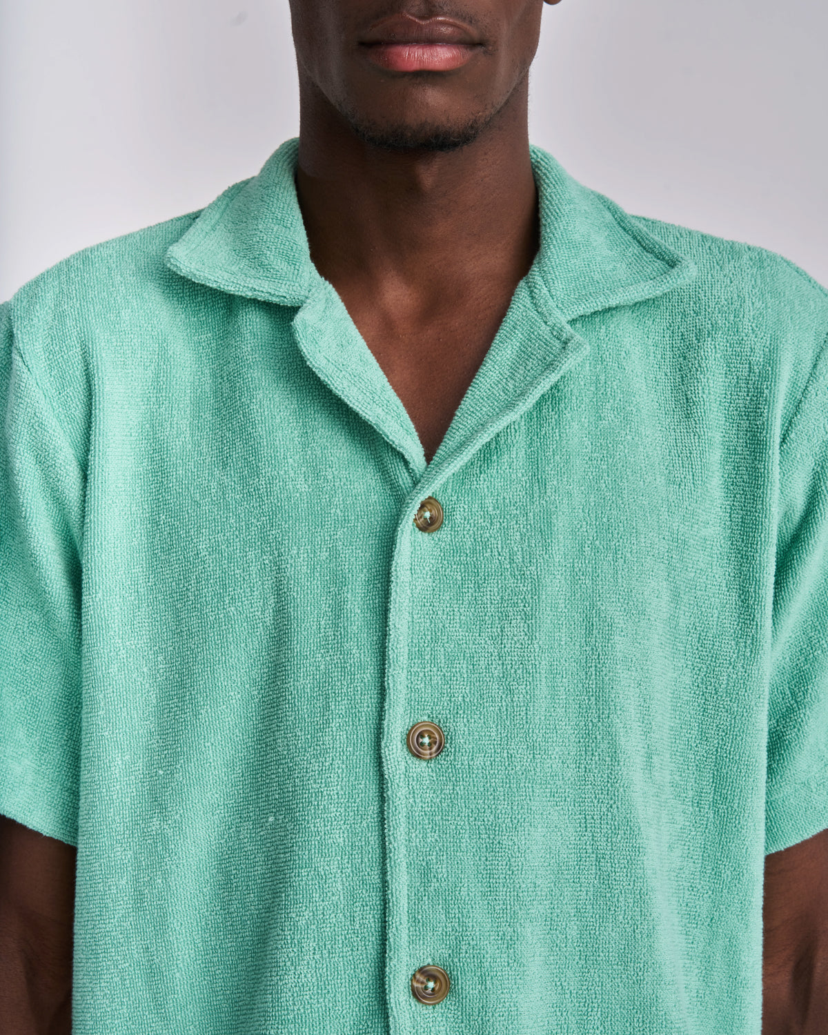Close-up of the tortoiseshell buttons on a Sage Green terry camp-collar shirt