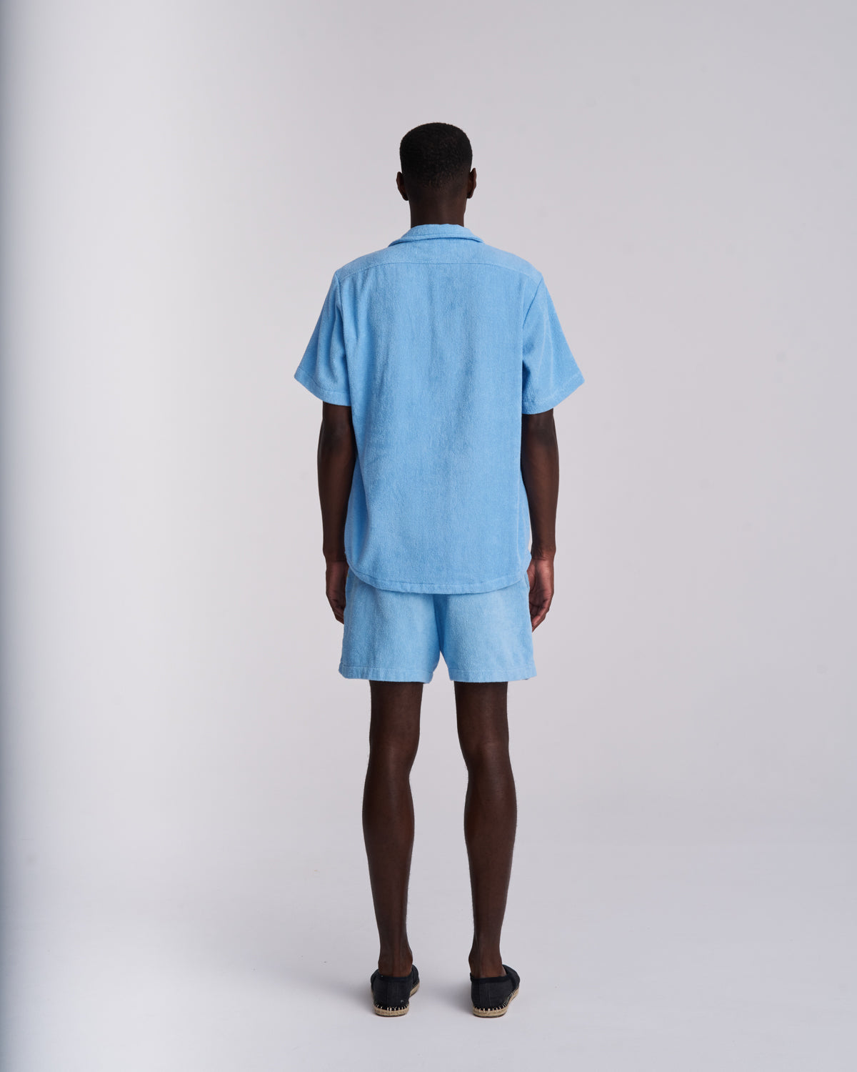 Back view of a Coastal Blue men's organic cotton terry camp-collar shirt with matching Coastal Blue terry shorts