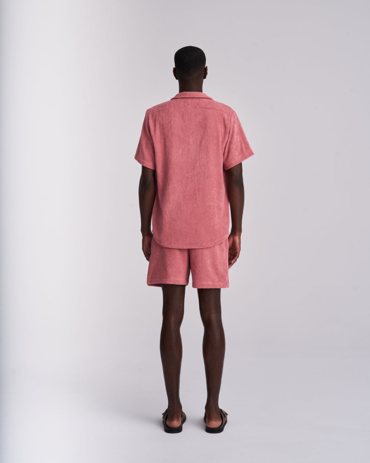Back view of dusty Rose men's terry camp-collar shirt styled with matching Dusty Rose terry shorts