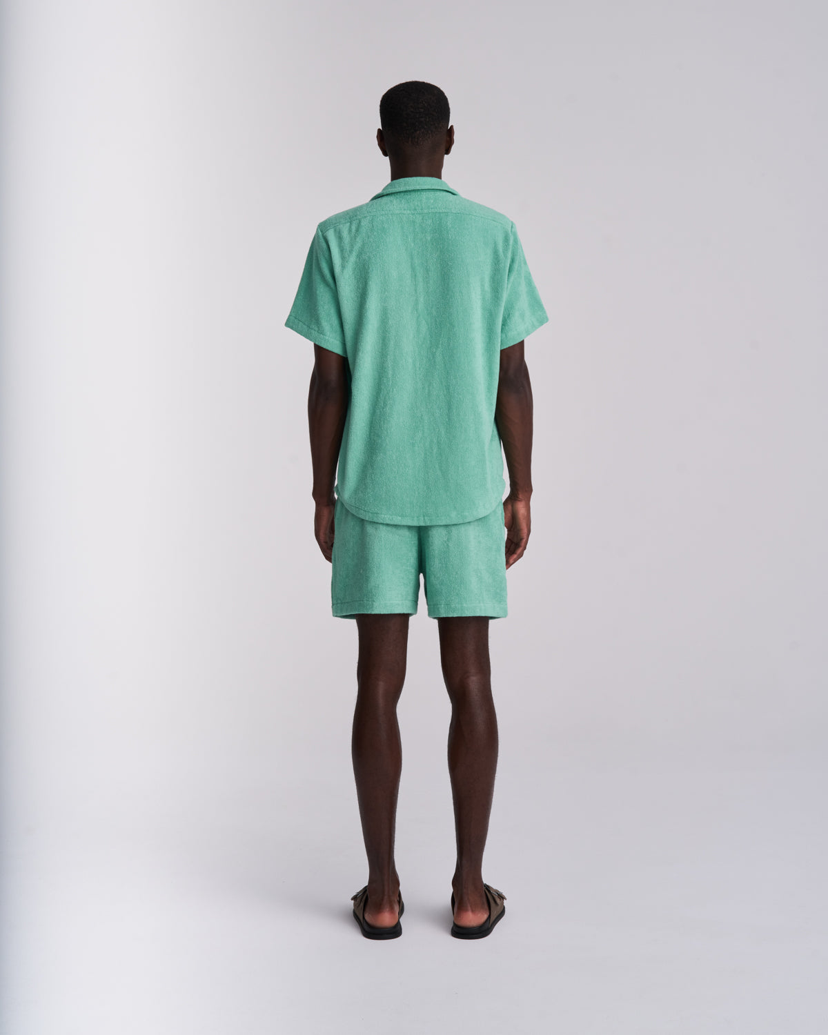 Back view of a Sage Green men's organic cotton terry camp-collar shirt with matching Sage Green terry shorts