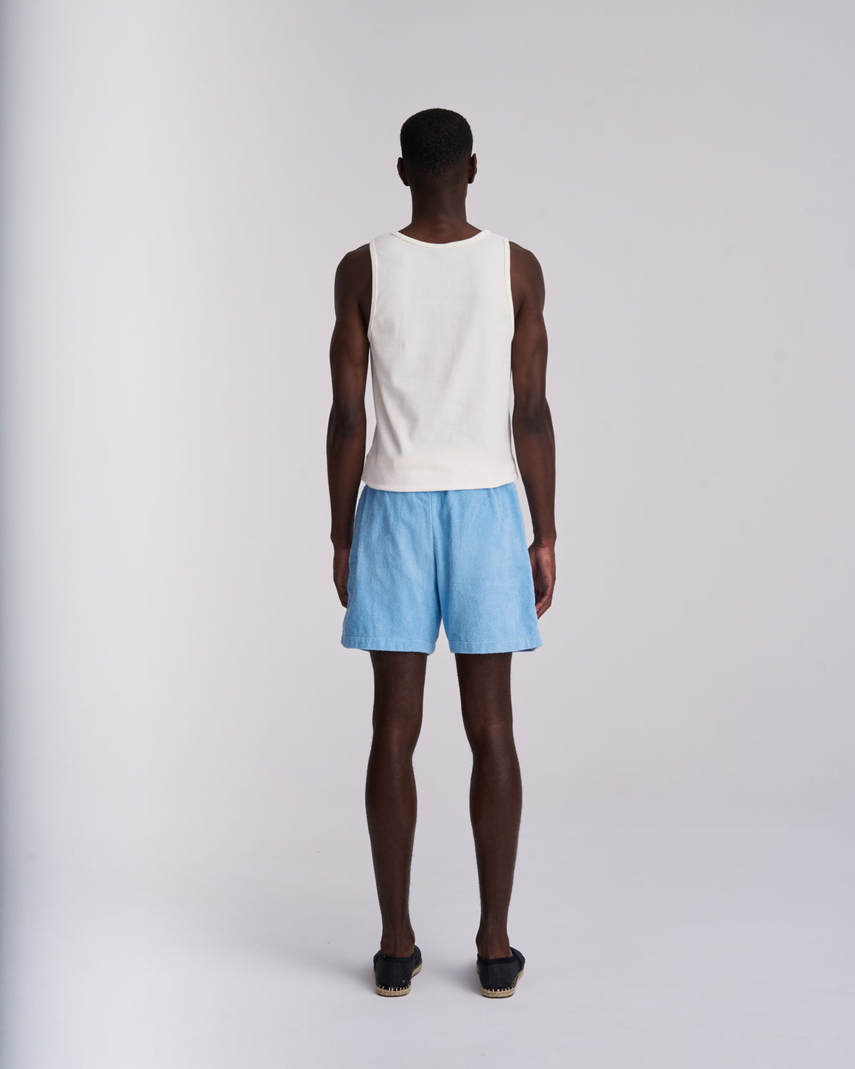 Man wearing Coastal Blue organic cotton terry shorts with elasticated waist, back view on a plain background