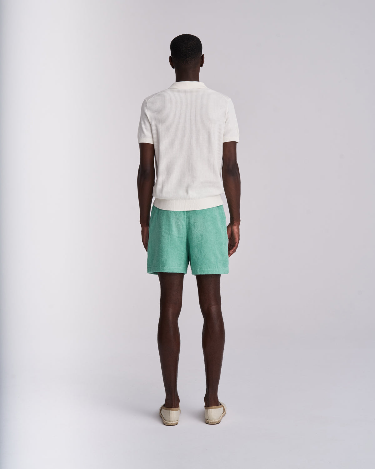Man wearing Sage Green organic cotton terry shorts with elasticated waist, back view on a plain background