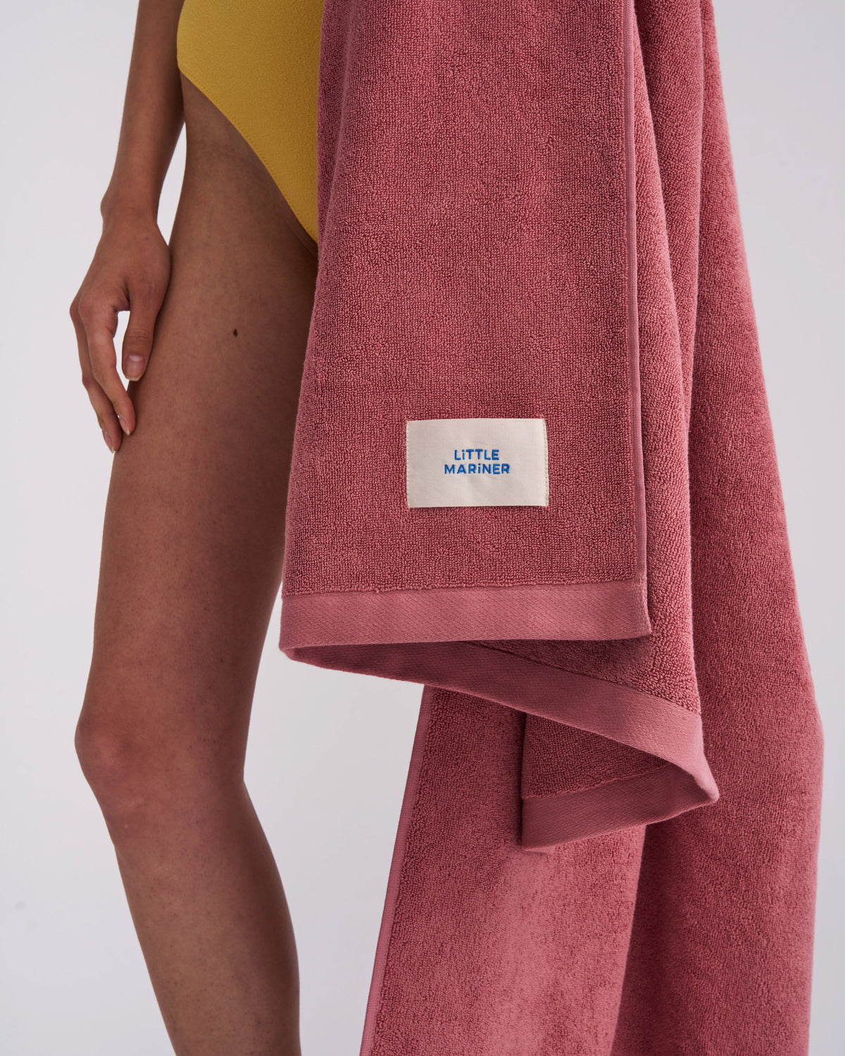 Dusty Rose organic cotton terry towel draped at the side with its woven label
