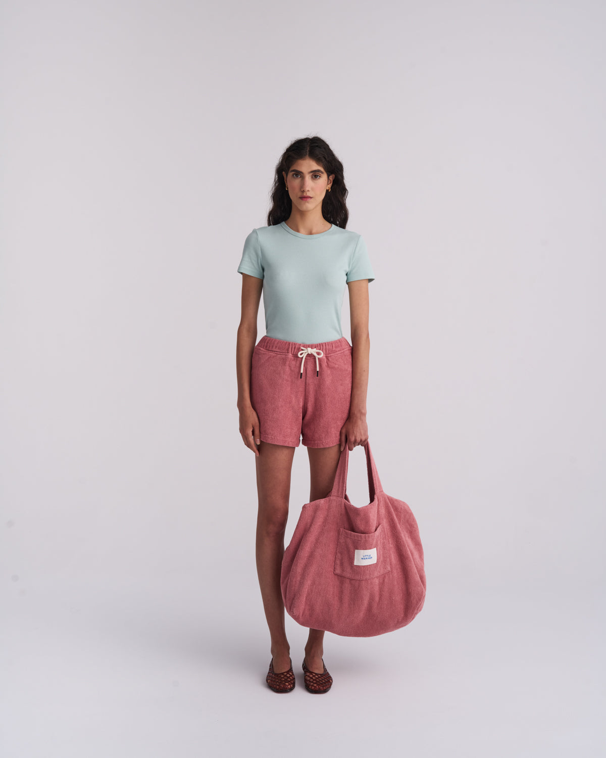 Woman holding a Dusty Rose organic cotton terry tote bag with Dusty Rose terry shorts, full length