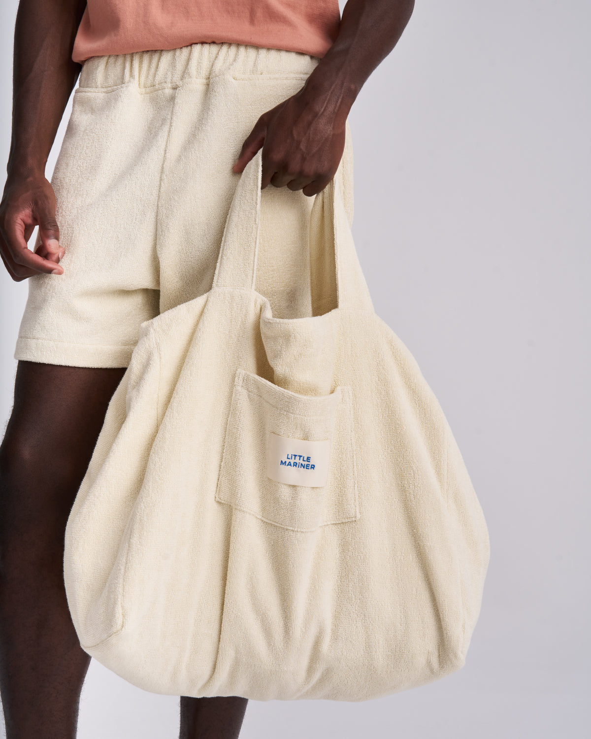 Off-White organic cotton terry tote bag held by the handles, front pocket and woven label