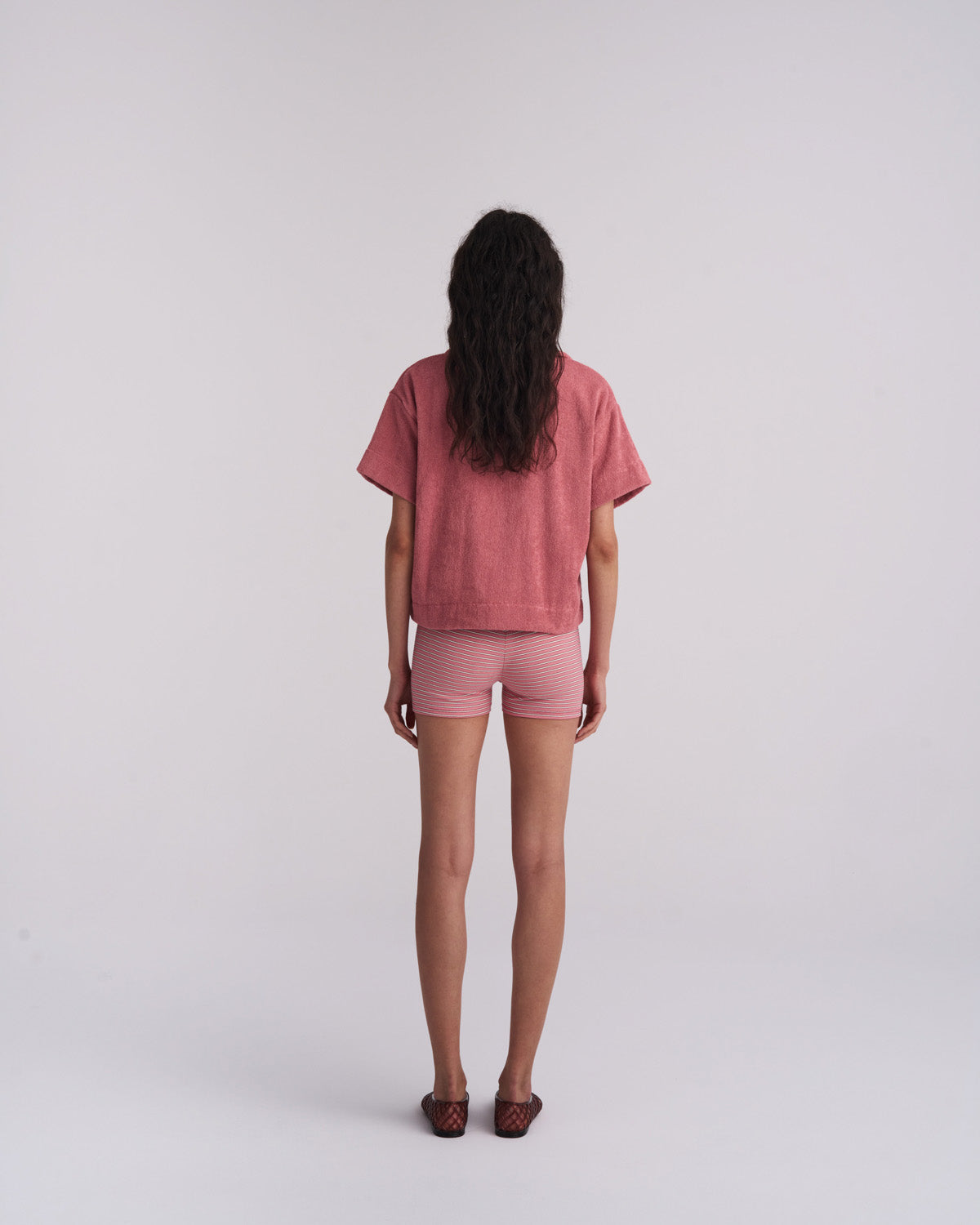 Woman in a Dusty Rose organic cotton terry camp-collar shirt with striped shorts, back view