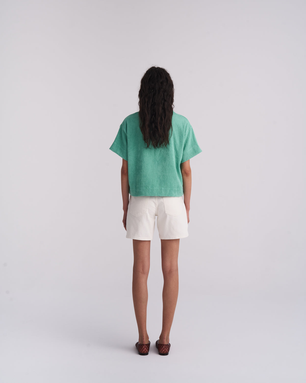 Back view of a woman in a Sage Green organic cotton terry camp-collar shirt