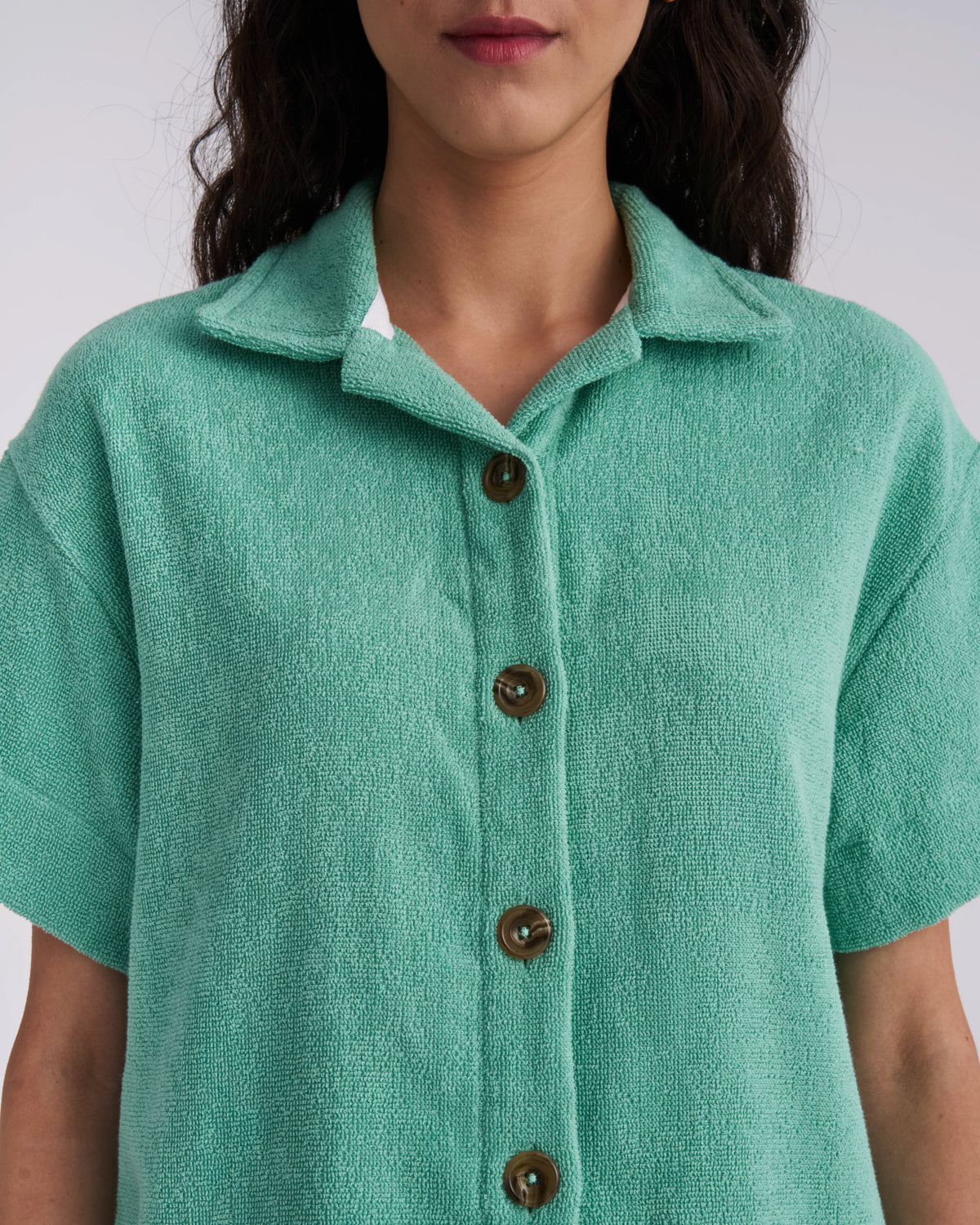Close-up of the collar and tortoiseshell buttons on a Sage Green women's terry camp-collar shirt